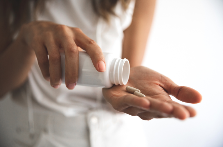 woman putting pill from bottle to hand